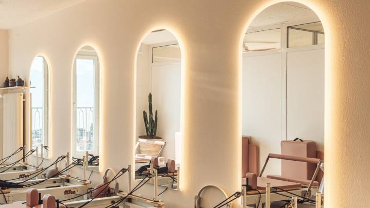Reformer studio at Moon Pilates Club with a row of backlit arched mirrors