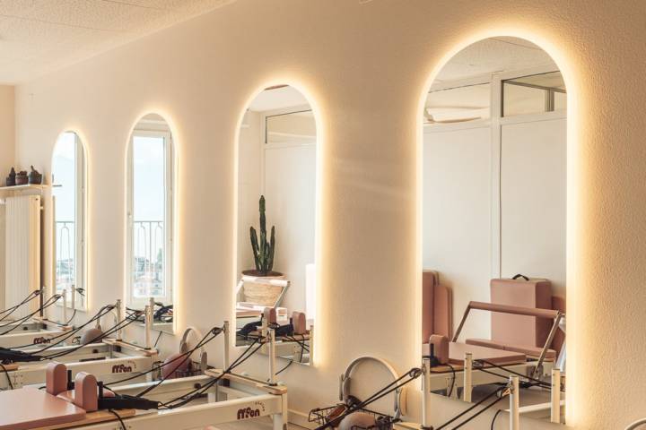 Reformer studio at Moon Pilates Club with a row of backlit arched mirrors