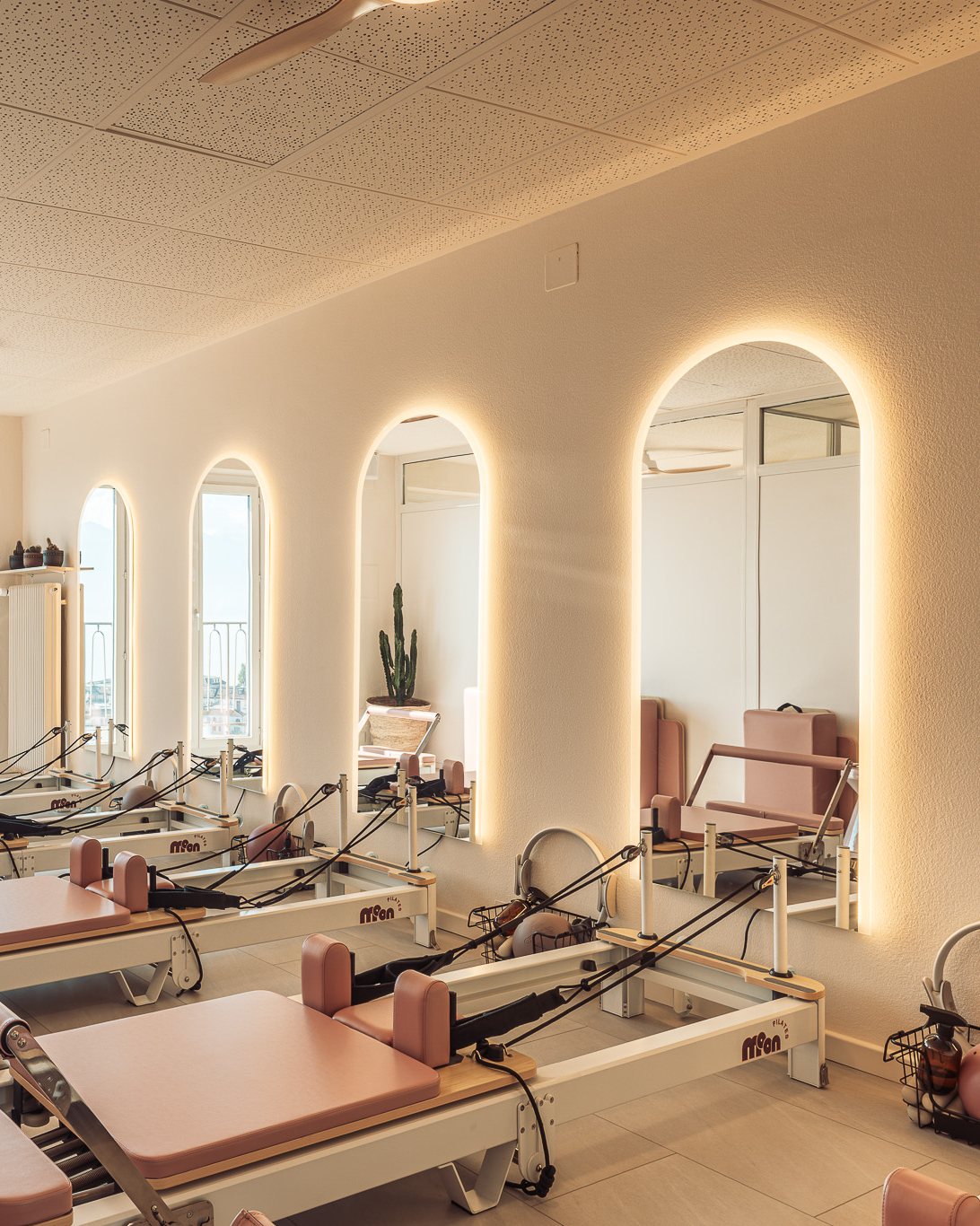 Reformer studio at Moon Pilates Club with a row of backlit arched mirrors