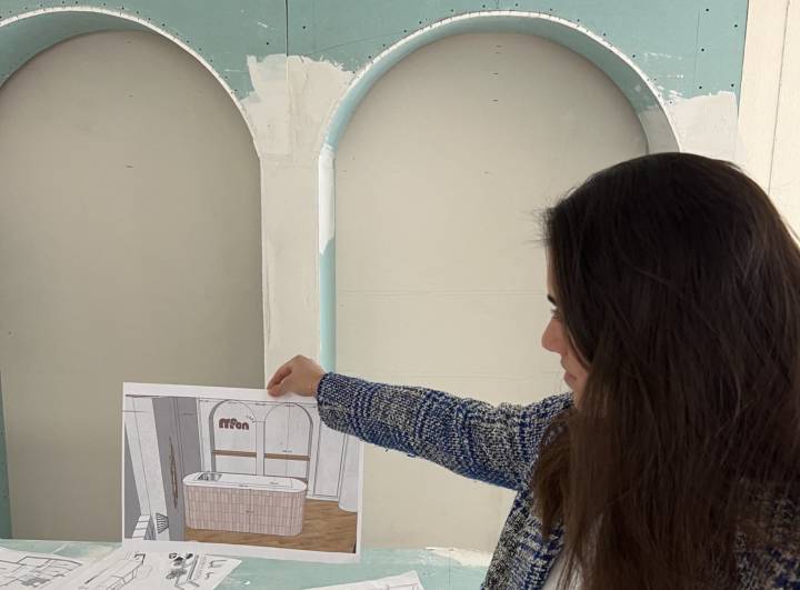 Alessia Di Dio holding the 3D render of the café in front of the unfinished plasterboard arches