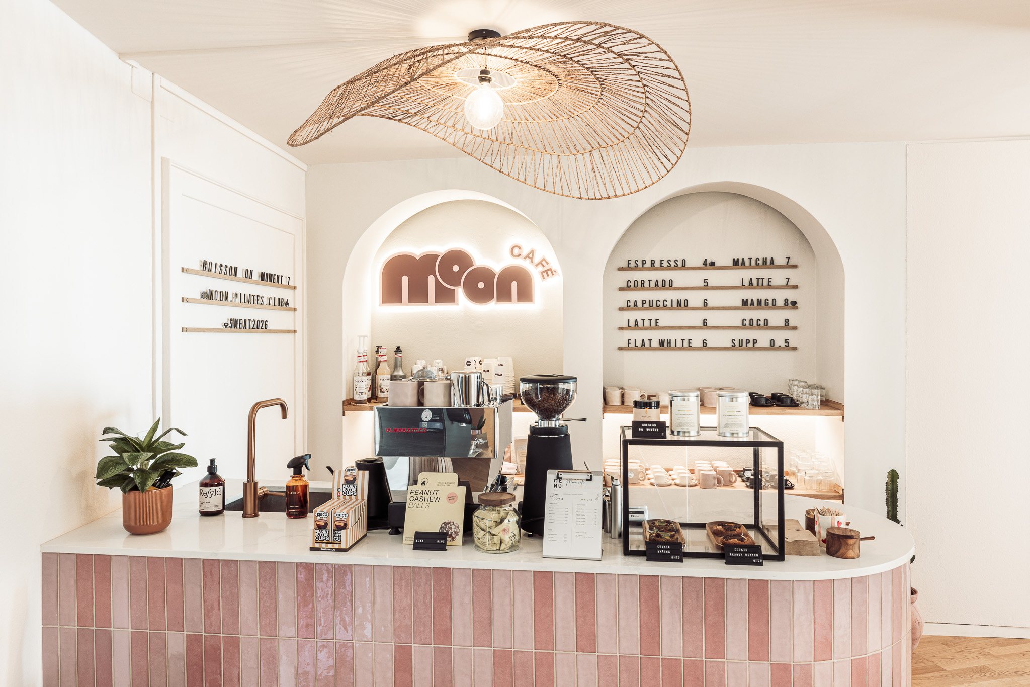 Moon Café bar seen from the front with pink tiles, arched niches and woven pendant light