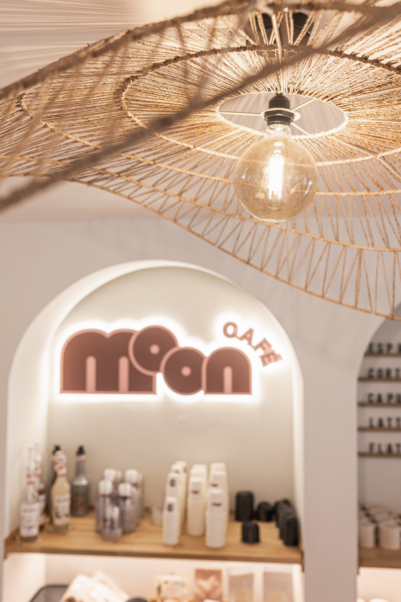 Backlit Moon Café sign inside an arched niche under a woven pendant