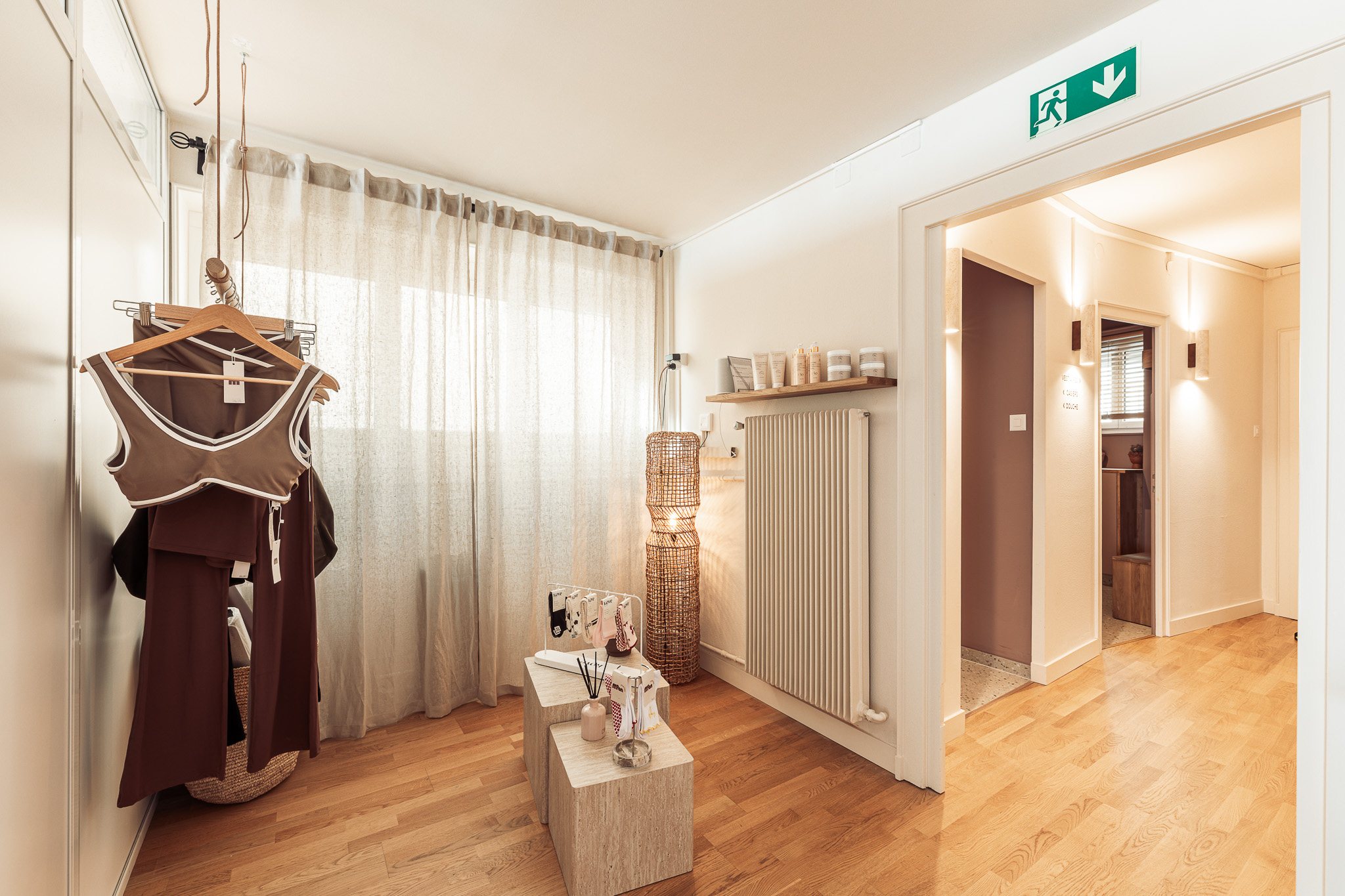 Retail corner with clothing rail, plinths and a view through to the changing rooms