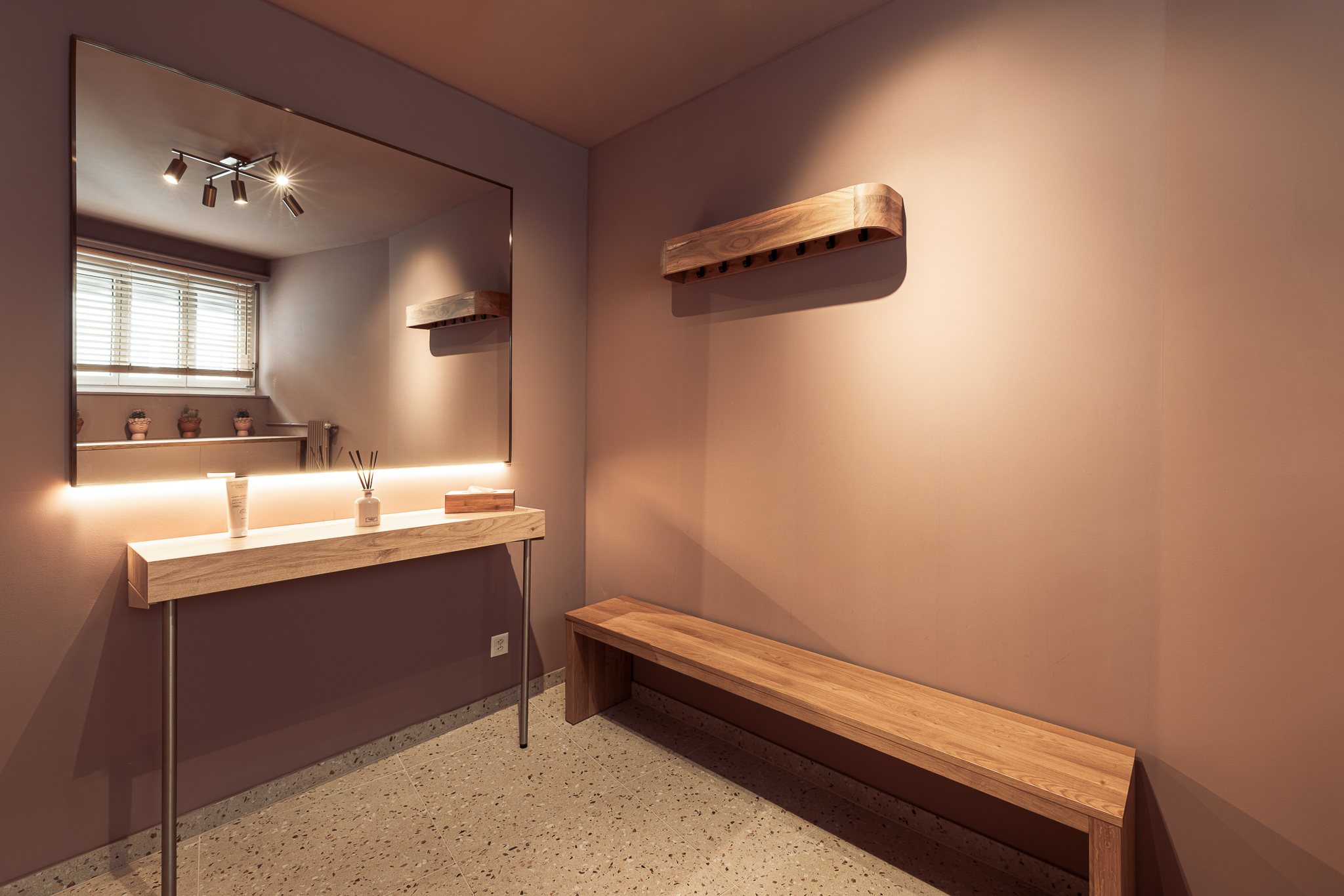 Changing room with backlit mirror, oak shelf and bench on a terrazzo floor