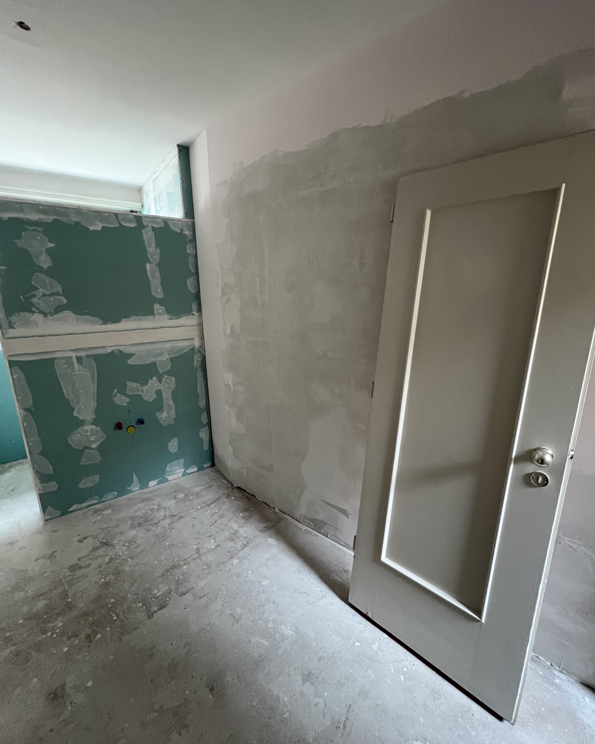 Changing room during works, with bare plasterboard and a door leaning against the wall