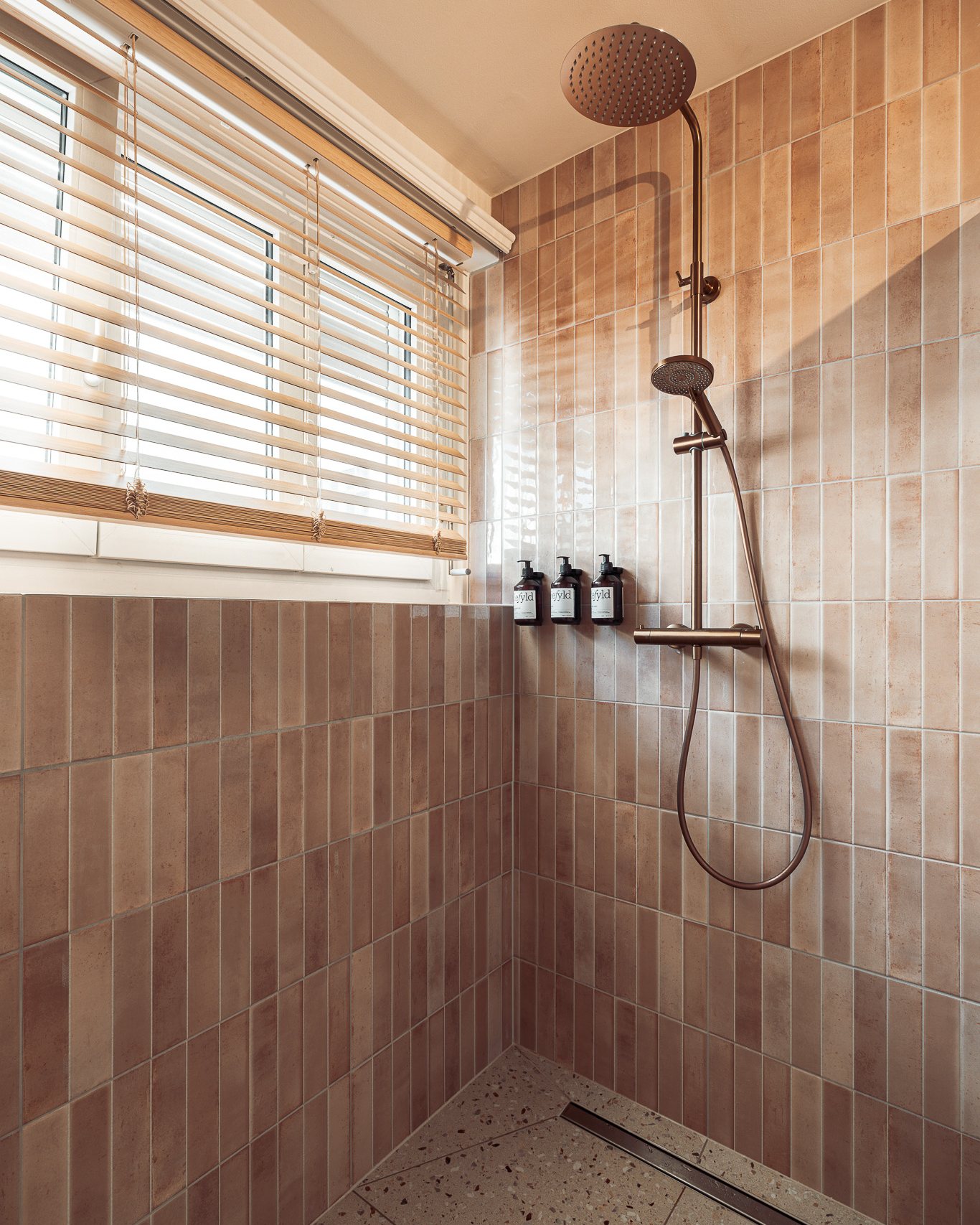 Walk-in shower with sand and blush tiles and a copper shower fitting